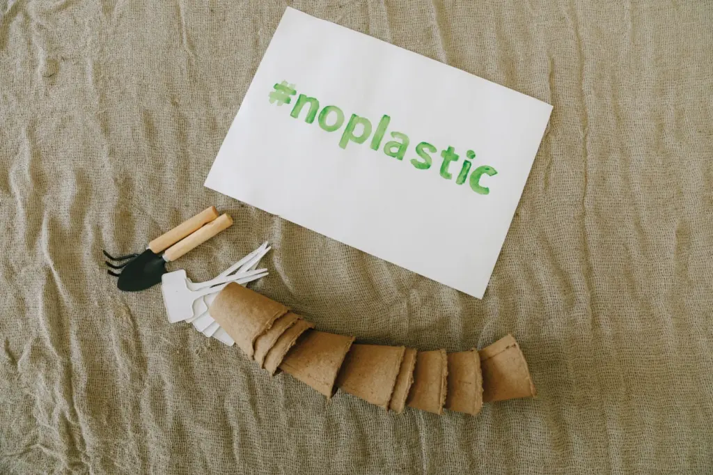 Biodegradable vs Compostable vs Recyclable: What's - Top view of sustainable gardening tools on fabric with '#noplastic' sign